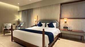 Une chambre d’hôtel avec un grand lit, deux tables de chevet, une chaise et un bureau.