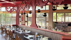 Un restaurant avec un long comptoir, des chaises en bois et des lampes suspendues.