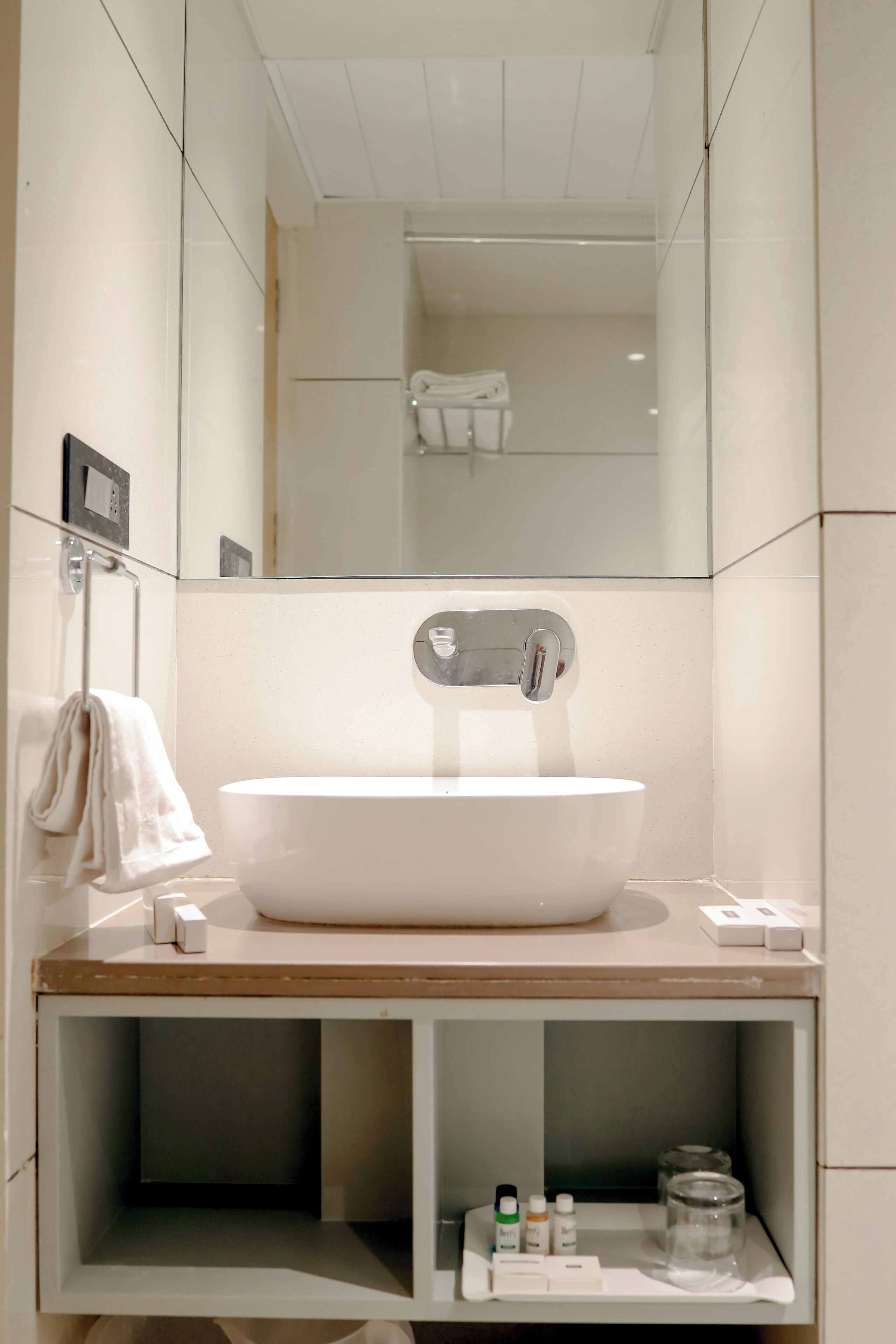 Un baño moderno con un lavamanos grande de color blanco, un espejo y un perchero para toallas.