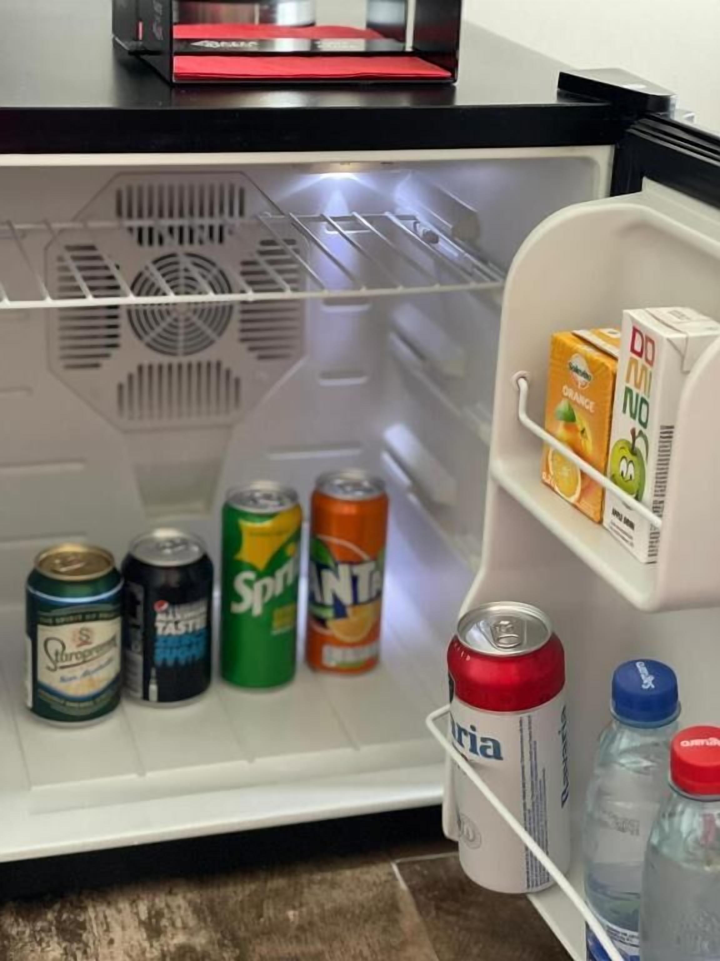 A refrigerator with a freezer compartment containing various beverages and a carton of orange juice.