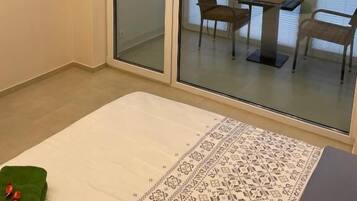 Una habitación con puerta corrediza de vidrio que da a un balcón con mesa y sillas.