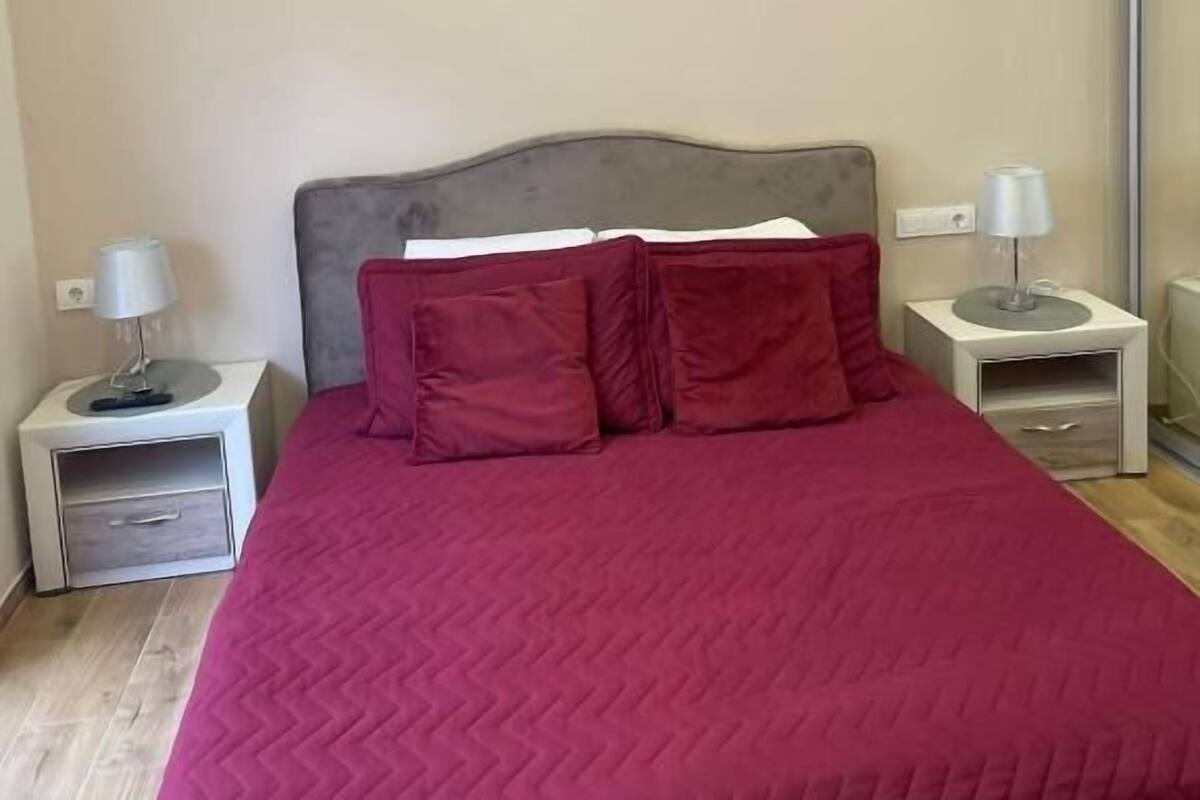 A bedroom with a bed, two bedside tables, and a nightstand.