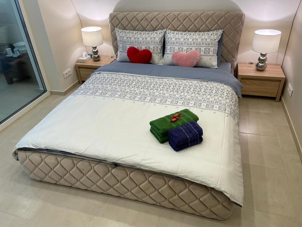 A neatly made bed with a quilted headboard, two bedside tables with lamps, and decorative pillows.