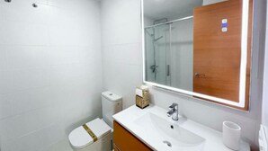 Une salle de bain moderne avec un lavabo blanc, un miroir et des toilettes.