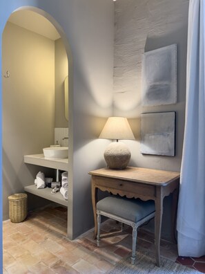 Un baño con lavamanos, espejo y tocador de madera con lámpara.