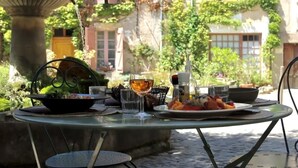 An outdoor dining area with a table set for two, featuring a variety of dishes and drinks. - Auberge du Presbytère (Saignon)