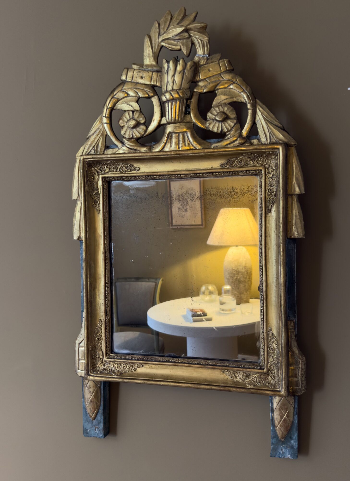 A wall-mounted mirror with ornate metalwork and a reflective surface.