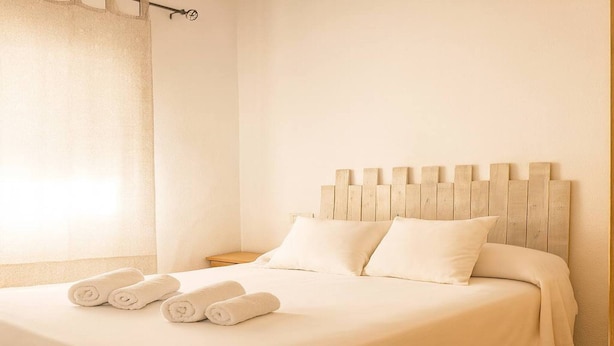 A neatly made bed with white linens and rolled towels, a wooden headboard, and a wooden floor. - El Palmar Family Hideaway Near the Sea (Vejer de la Frontera)