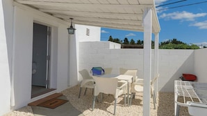 A covered outdoor seating area with a table and chairs, a door, and a white wall. - El Palmar Family Hideaway Near the Sea (Vejer de la Frontera)