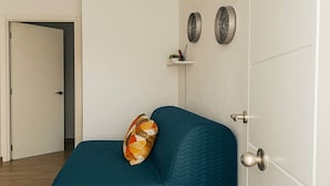 A teal sofa with a geometric-patterned pillow, a white door, and two wall-mounted decorative plates. - El Palmar Family Hideaway Near the Sea (Vejer de la Frontera)