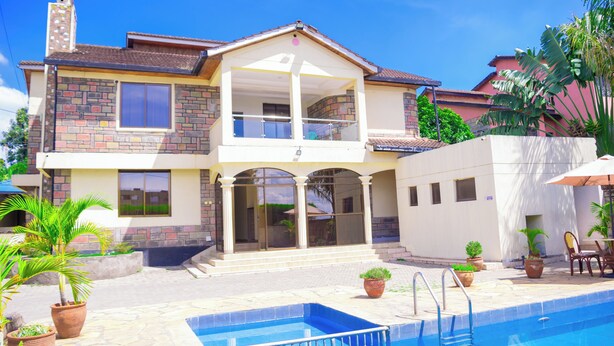 Ein zweistöckiges Haus mit Swimmingpool, Kübelpflanzen und einer Terrassenanlage.