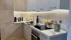 A modern kitchen with a built-in stove, a sink, and a countertop with various kitchen items. - Sweet Holidays (Magomadas)