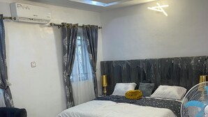 A modern bedroom with a large bed, a bedside table, a chair, and a ceiling fan. - Make Yourself at Home with Luxury Living and Unmatched Comfort (Osogbo)