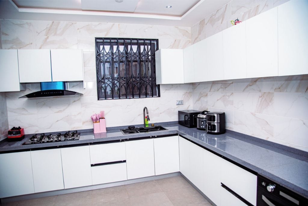 A modern kitchen with white cabinets, a gas stove, a microwave, and a coffee maker.