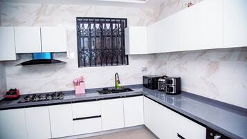 A modern kitchen with white cabinets, a gas stove, a microwave, and a coffee maker.