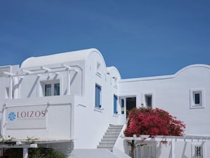A white building with a sign for Loizos Stylish Residences. - Loizos Apartments (Santorini)