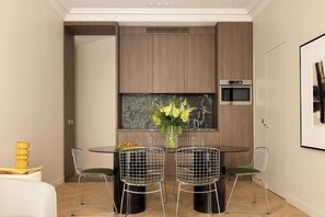 Een moderne keuken met een eethoek, met een ronde tafel, draadstoelen en inbouwapparatuur.