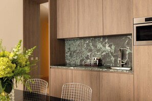 Eine moderne Küche mit Holzschränken, einer Marmor-Spritzschutzleiste und Edelstahlgeräten.