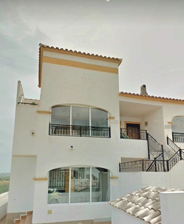 Un bâtiment à deux étages, à l’extérieur blanc, doté de grandes fenêtres et d’un balcon avec une rambarde noire.