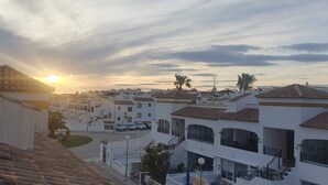 Un quartier résidentiel avec des bâtiments blancs, une rue et un coucher de soleil.