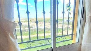 Une pièce dotée d’une fenêtre ornée de barreaux et offrant une vue sur un paysage verdoyant.