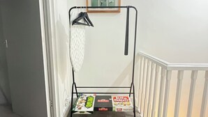 Um corredor com uma estante de metal com livros e um quadro pendurado na parede.