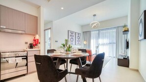 A modern kitchen with a built-in oven and a dining area with a round table and black chairs. - Oshima Act Two Downtown 1BR Burj Khalifa (Dubai)