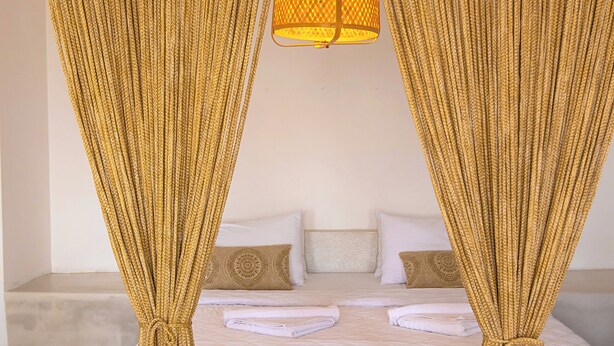 A bedroom with a bed, curtains, and a table.