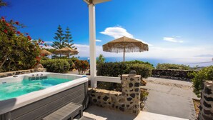 A hot tub with a stone wall and a wooden deck, overlooking a scenic view.