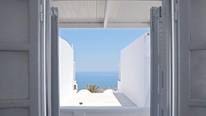 An open doorway leading to a balcony with a view of the sea.