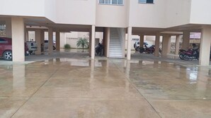 A covered parking area with multiple vehicles, including cars and motorcycles, and a central staircase leading to an upper level. - Apartment for discerning people. (Barreiras)