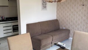 A modern living room with a brown sofa, a glass coffee table, and two chairs. A unique wooden light fixture hangs above the sofa. - Apartment for discerning people. (Barreiras)
