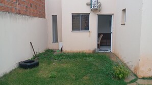 A small, enclosed outdoor area with a grassy lawn, a tire, and a brick wall. - Apartment for discerning people. (Barreiras)
