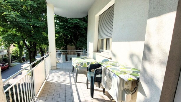 A balcony with a table and chairs, a fan, and a window. - CN028 - Cesenatico, Villa Federica - comfortable two-bedroom apartment with parking space (Cesenatico)