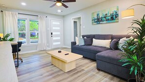 Ein modernes Wohnzimmer mit einem dunkelgrauen Sofa, einem Holztisch und einem Deckenventilator.