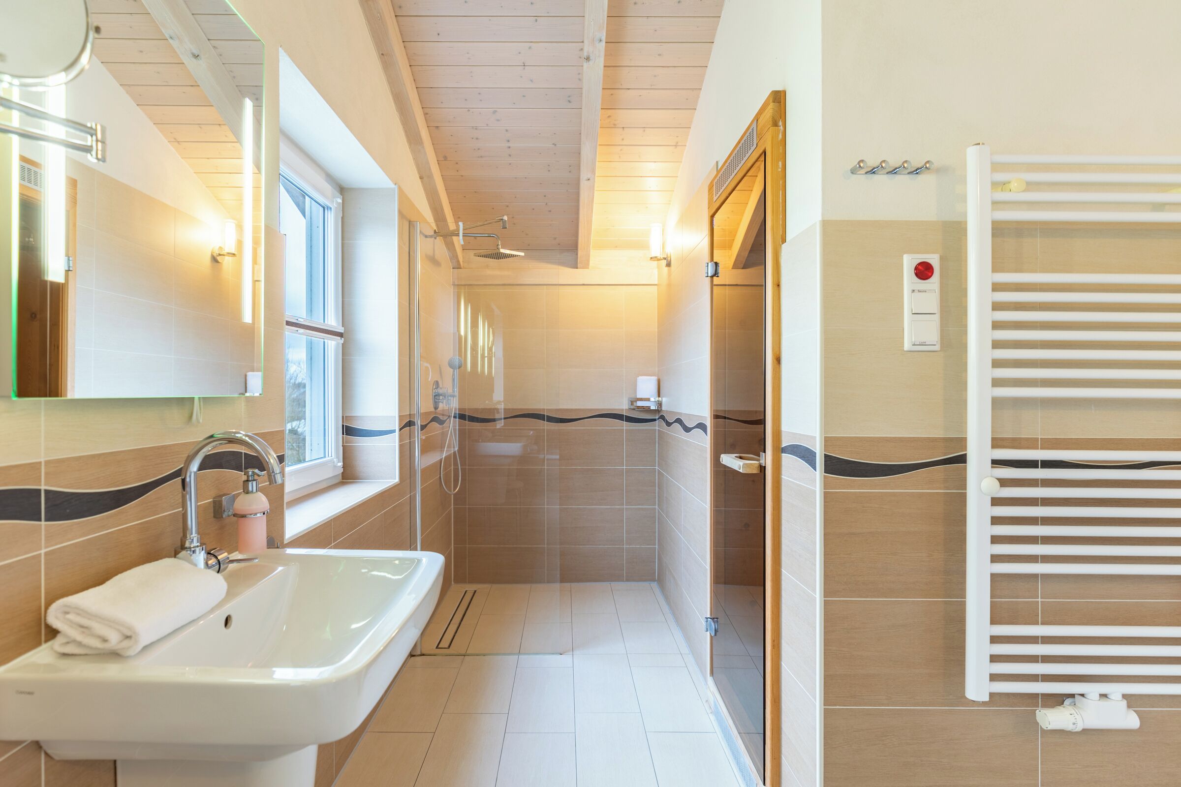 Ein modernes Badezimmer mit Waschbecken, Spiegel, Dusche und Handtuchhalter.