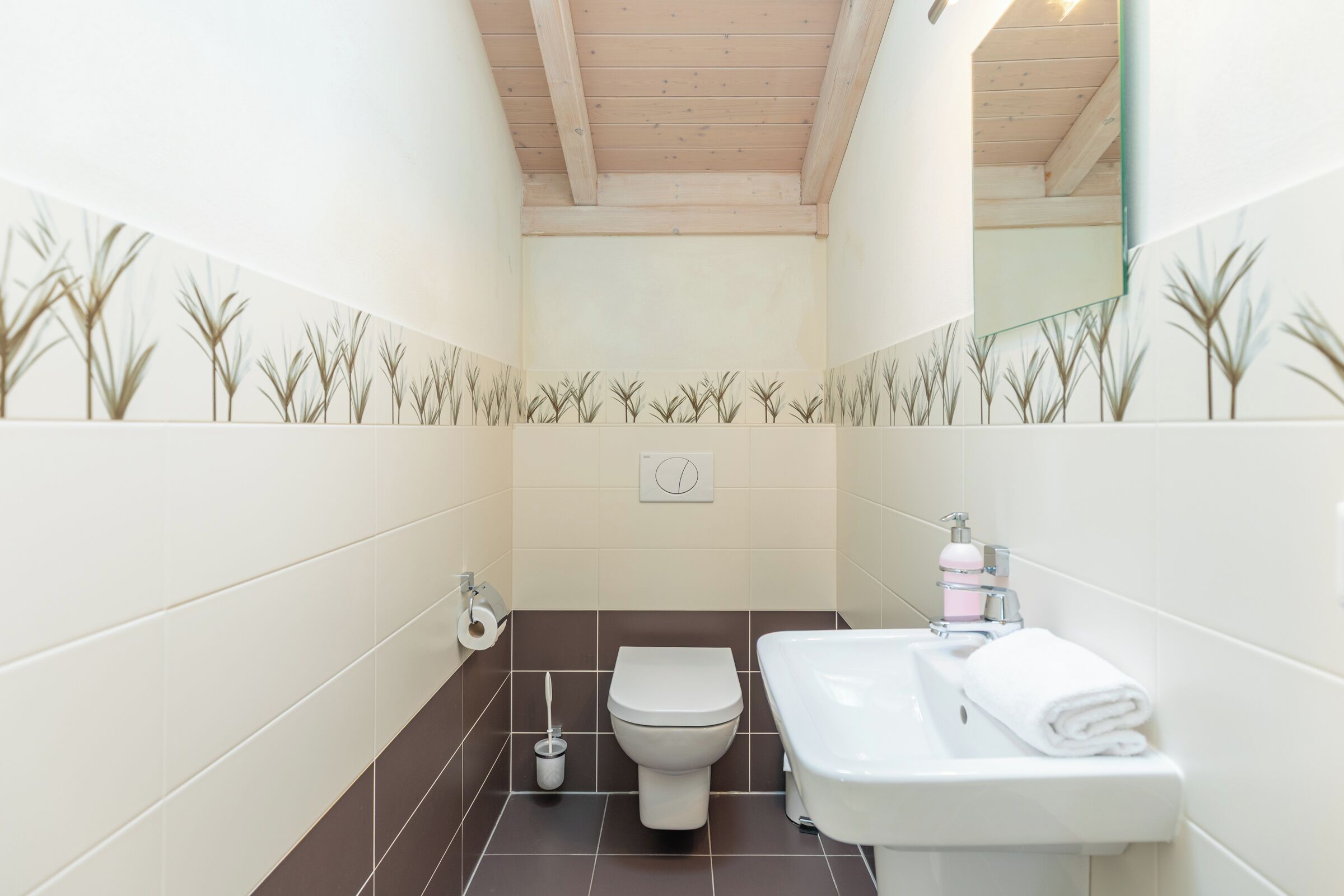 A bathroom with a toilet, sink, and mirror.