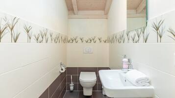 A bathroom with a toilet, sink, and mirror.