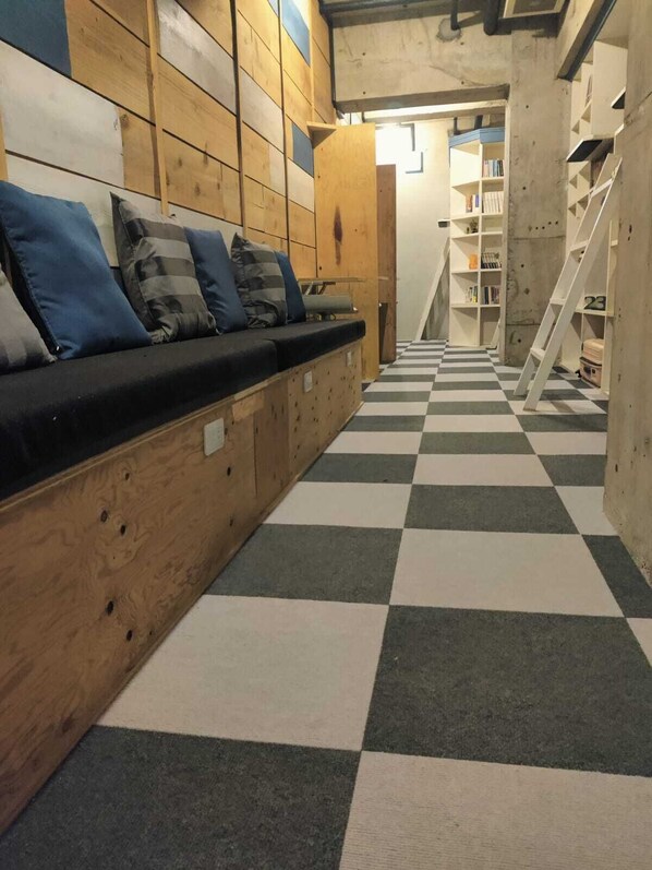 A checkered floor, wooden walls, a sofa with cushions, and a staircase.