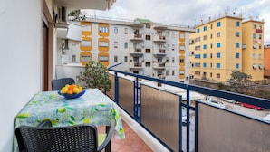 Un balcón con una mesa, sillas, un frutero y vistas a edificios altos.