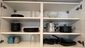 Una cucina con mobili bianchi, un lavello in acciaio inossidabile e diversi utensili e elettrodomestici.