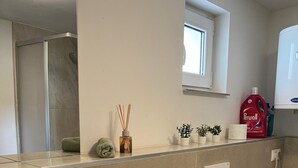 Un bagno con un lavandino bianco, uno specchio, un WC e una finestra.