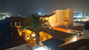 Um edifício com telhado plano e uma palmeira em primeiro plano.