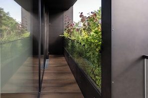 A narrow corridor with a wooden floor, glass walls, and a metal railing. - Spacious modern apartment-feels like home - short or long, park view - center! (Linz)