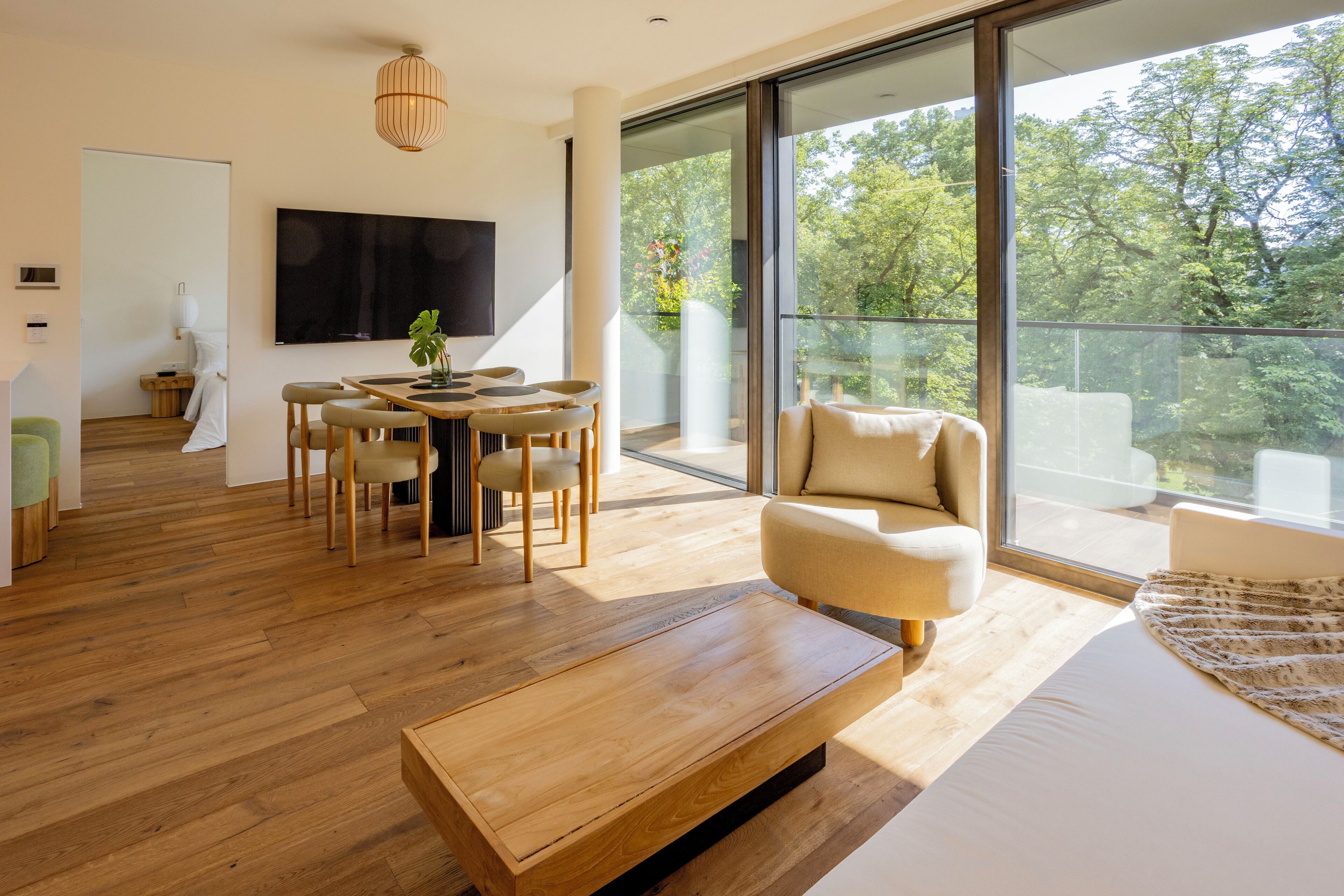 A modern living room with a wooden coffee table, a sofa, and a dining area with chairs and a table.