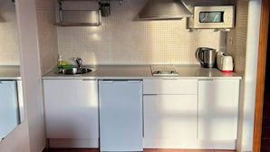 Una cuina compacta amb microones, rentapelats i escorredora.