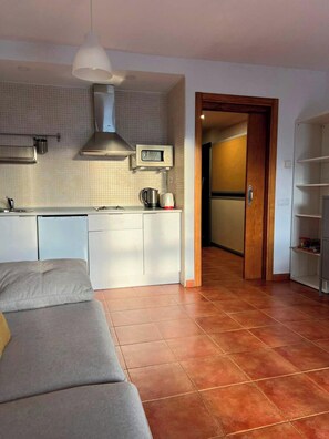 A compact living space with a kitchenette, a sofa, and a door leading to a hallway. - Group Getaway Near Ski Slopes (Monachil)