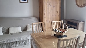 Een gezellige kamer met een houten eettafel, stoelen, een bank en een kast.