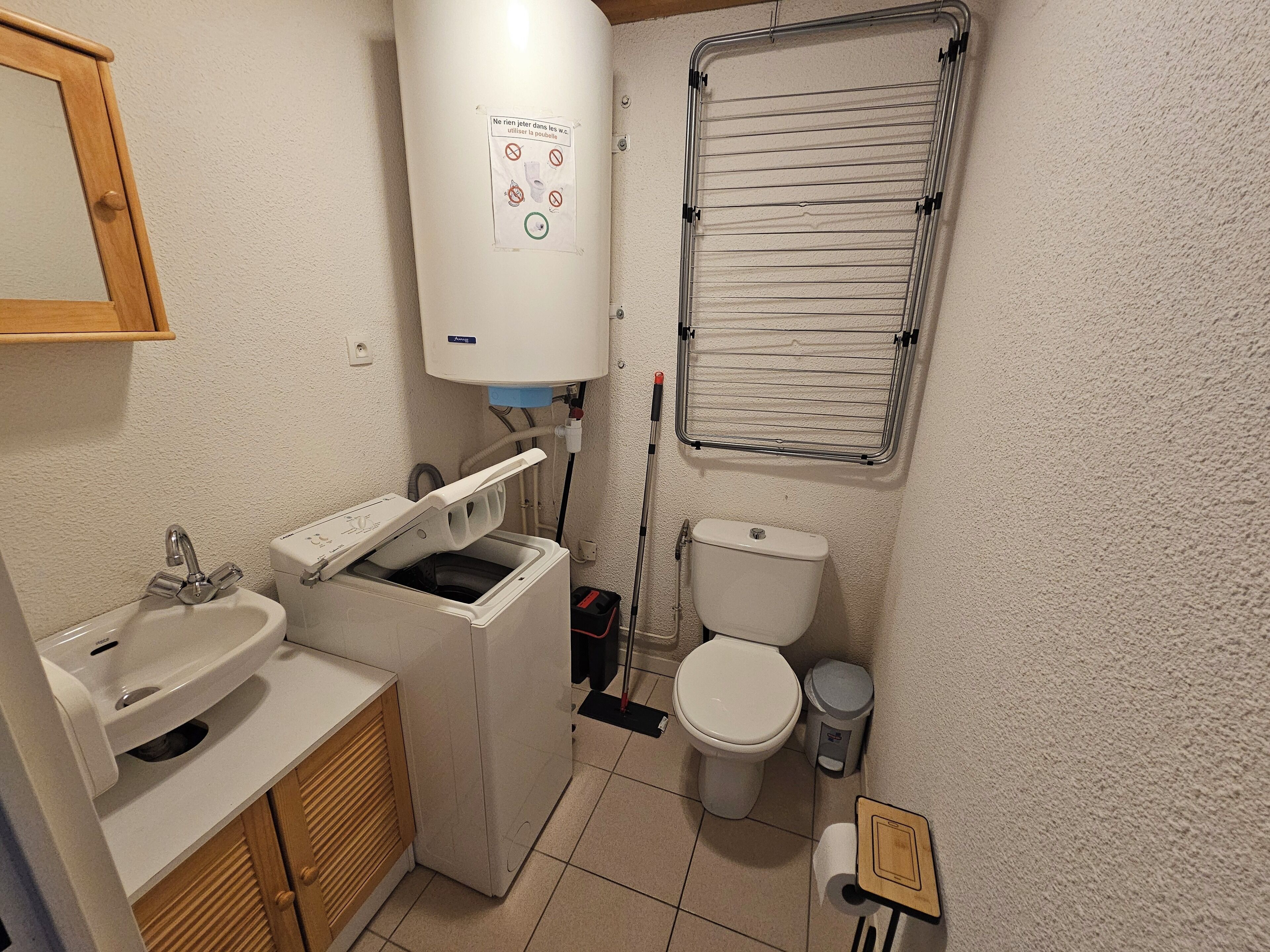 A compact bathroom with a sink, toilet, and a small washing machine.