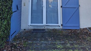 Een huis met een blauwe deur, een blauwe garagepoort en een klein portaaltje met een witte balustrade.